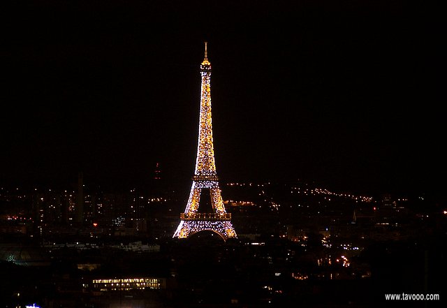 At night the Eiffel tower sparkles, lit by thousands of bright blinking lights.